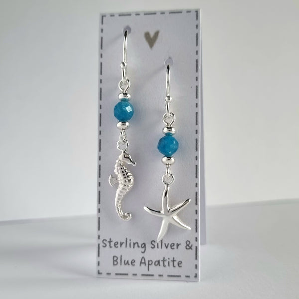 Ocean themed silver earrings with blue Apatite gemstones. One earring features a silver starfish and the other earring features a silver starfish.