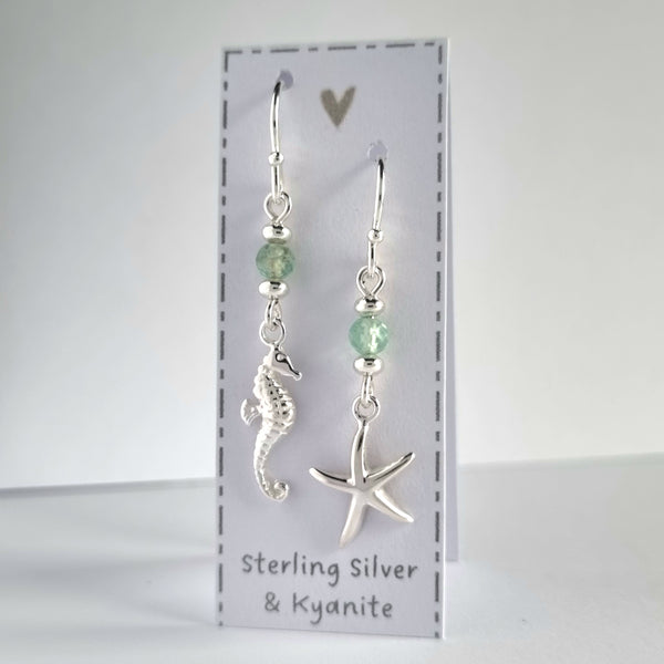 Ocean themed silver earrings with a silver starfish on one earring and silver seahorse on the other earring. Both earrings feature a sparkly pale green kyanite gemstone bead