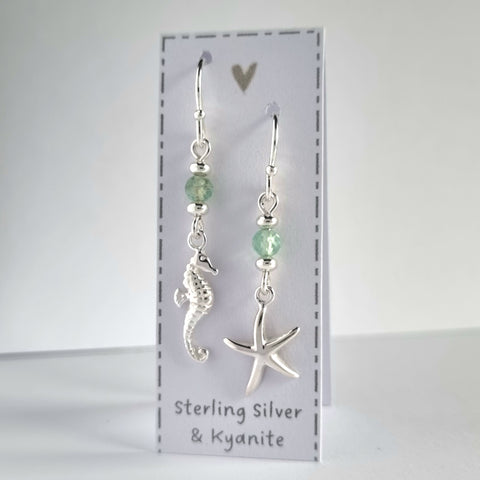 Ocean themed silver earrings with a silver starfish on one earring and silver seahorse on the other earring. Both earrings feature a sparkly pale green kyanite gemstone bead