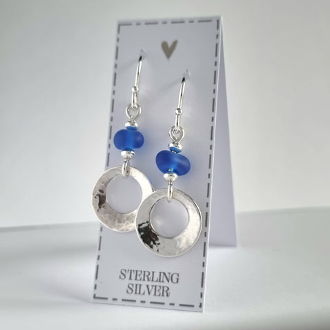 Beautiful, hammered silver earrings, featuring genuine sea glass beads in a deep cobalt blue colour. These sterling silver offset circles feature a gentle hammered texture and a softly concave finish.